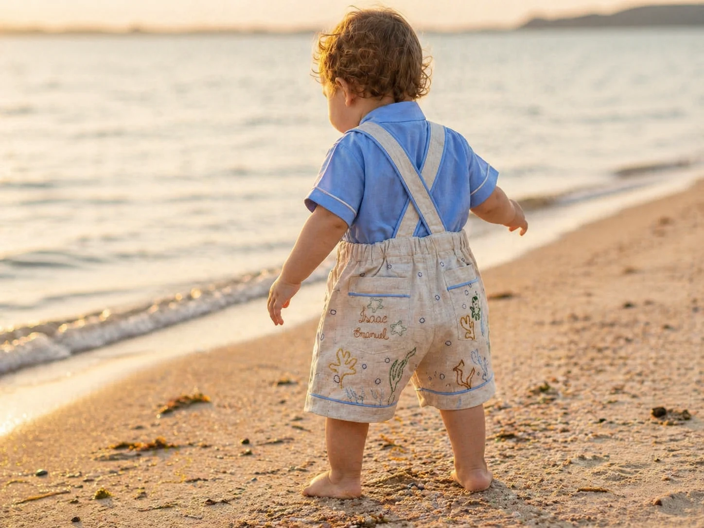 Ensaio fotográfico de praia · Jardineira Premium em linho cru com vivo azul bebê + Camisa Social azul claro · criança barefoot na areia ao golden hour · book de família